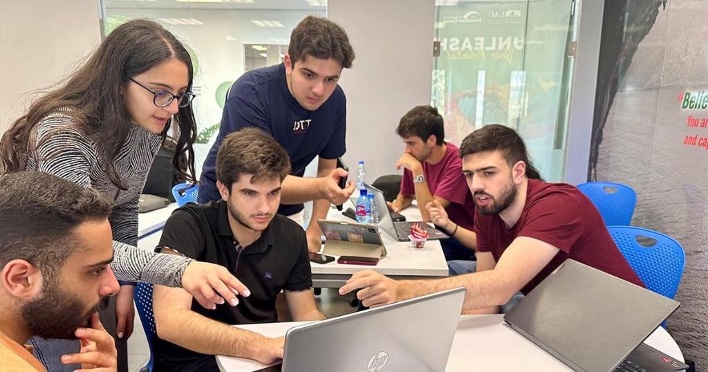 Young people collaborating around laptops during a learning activity